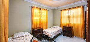 een slaapkamer met 2 aparte bedden en oranje gordijnen bij casa bayaguana in Bayaguana
