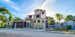 un viejo edificio con una valla delante en casa bayaguana, en Bayaguana