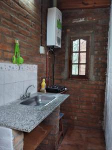 a kitchen with a sink and a brick wall at La Vuelta del Río in Panaholma