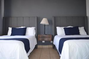um quarto de hotel com duas camas com almofadas azuis e brancas em Hotel CASA PETRI em Ensenada