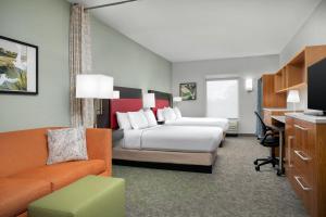 a hotel room with two beds and a desk at Home2 Suites by Hilton Tallahassee State Capitol in Tallahassee