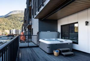 Villa 23 Cabot Peaks by Revelstoke Vacations في ريفيلستوك: حوض استحمام ساخن على شرفة المبنى