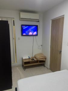 - une chambre avec un lit et une télévision murale dans l'établissement Hostel HA, à Carthagène des Indes