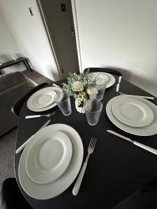 a black table with white plates and utensils on it at Timber Court Apartments in Central Location with FREE Parking and Netflix by RockmanStays in Stifford