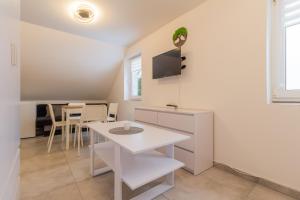 a dining room with a white table and a tv at LIPNO Moss Apartment in Lipno nad Vltavou