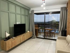 een woonkamer met een flatscreen-tv en een tafel bij Flat Eco Resort Carneiros in Praia dos Carneiros