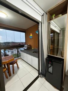 a kitchen with a large window and a table with a counter at Flat Eco Resort Carneiros in Praia dos Carneiros