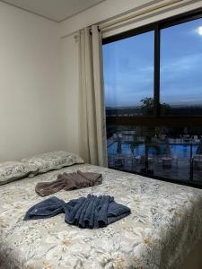 a bed with a pile of clothes on it in front of a window at Flat Eco Resort Carneiros in Praia dos Carneiros