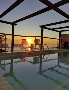 a swimming pool with a sunset in the background at Apto 2 dorm com vista para o mar in Capão da Canoa