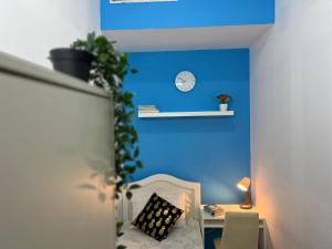 a room with a blue wall and a desk with a clock at Bachelor Partition Room in Tecom in Dubai