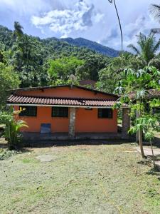 ein kleines orangenes Haus mit einem Berg im Hintergrund in der Unterkunft Casa Laranja in Angra dos Reis