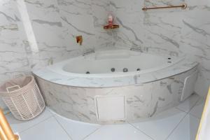a white bath tub in a bathroom with marble walls at Homes of Ace Diamond in Pretoria