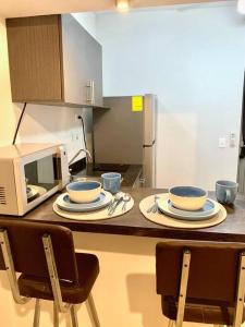 a kitchen counter with plates and cups and a microwave at Departamento Regiomontano in Monterrey