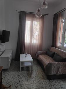een woonkamer met een bank en een tafel bij Το σπίτι με τις βουκαμβίλιες in Ayia Evfimia