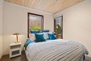 um quarto com uma cama com almofadas azuis e uma janela em Am Meer at Cora Lynn em Lorne