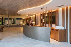 a lobby with a bar with a person standing in the background at Infinity Hotel & Conference Resort Munich in Unterschleißheim