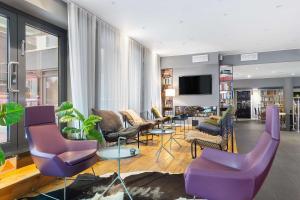 a living room with purple chairs and a flat screen tv at Aiden by Best Western Stockholm Kista in Stockholm