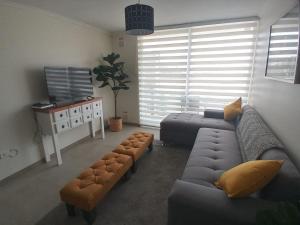 un soggiorno con divano e 2 pouf di ALOJAMIENTO BAHIA PELICANOS EXTENSAS y AMPLIAS VISTAS AL JARDIN a La Serena