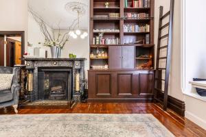a living room with a fireplace and a book shelf at Elwood Manor - A Restored Art-Deco Gem in Melbourne