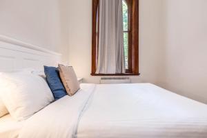 a white bed in a room with a window at Elwood Manor - A Restored Art-Deco Gem in Melbourne