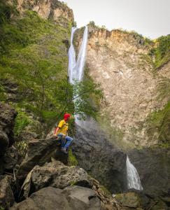 a man sitting on a rock in front of a waterfall at MAYU in San Agustín