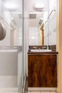 a bathroom with a sink and a glass shower at Elwood Manor - A Restored Art-Deco Gem in Melbourne