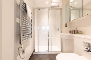 a white bathroom with a shower and a toilet at Lotus - Sleeps 5 in Bracknell