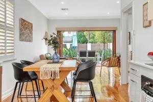 a kitchen and dining room with a wooden table and chairs at Gladstone Gardens - Family Comfort in North Brighton in Adelaide