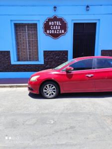 un coche rojo estacionado frente a un hotel casino imperial en HotelCasaMorazanGranadaNicaragua, en Granada