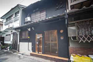 a black building with wooden doors and a balcony at Tabitaimu-Sumiyoshiharesora - Vacation STAY 15843 in Osaka