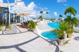 a pool with chairs and palm trees on a building at Mare Condo Vacacional Playa del Carmen in Playa del Carmen