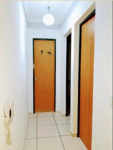 um corredor com duas portas castanhas e piso em azulejo em CantinhoDaAline2-Expo-Aeroporto-18981391712 em Araçatuba