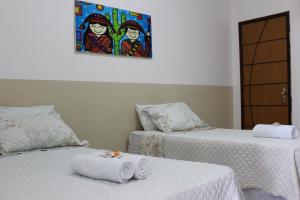 a room with two beds and a painting on the wall at Hotel Mandacaru in Piranhas