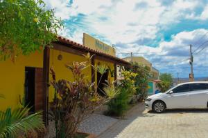 a white car parked in front of a yellow building at Hotel Mandacaru in Piranhas