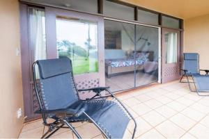 een balkon met 2 stoelen en een bed op een veranda bij Oceanview Moloka'i Studio in Maunaloa