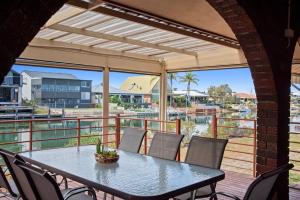 una mesa y sillas en una terraza con vistas al agua en Canal Tranquillity - Restful Water Retreat, en South Yunderup