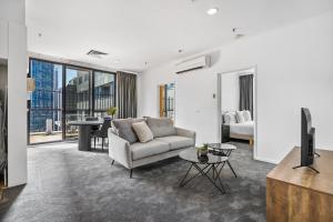 ein Wohnzimmer mit einem Sofa, einem TV und einem Tisch in der Unterkunft Family Friendly Getaway on Flinders Street in Melbourne