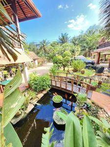 a garden with a pond with plants and a bridge at Lanta Thai Homestay in Ko Lanta