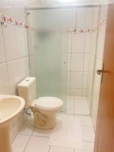 a white bathroom with a toilet and a shower at Pousada Lirio do Vale in Cachoeira Paulista