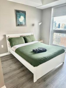 a bedroom with a large white bed with green sheets at Cozy 2 Bedroom by Eaton Centre Mall in Toronto