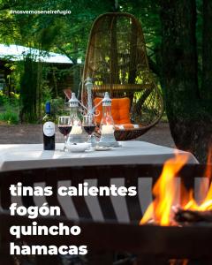 a table with wine glasses on it next to a fire at Refugio Invernalia in Las Trancas