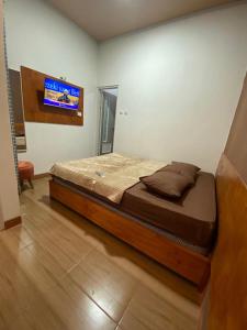 Bett in einem Zimmer mit einem TV an der Wand in der Unterkunft Resy home syariah dekat alun2 wonosobo in Kalianget
