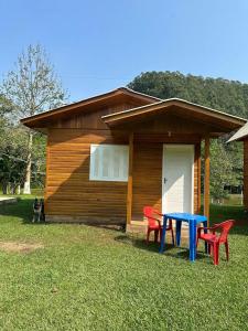 ein Haus mit einem blauen Tisch und zwei roten Stühlen in der Unterkunft Sítio Recanto Nativo in Palmitos