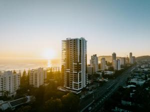 a tall building in a city with the sun setting at Sandbar Burleigh - Official in Gold Coast