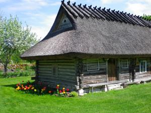 an old log cabin with a thatched roof and flowers at Käspri Farmstay in Koguva