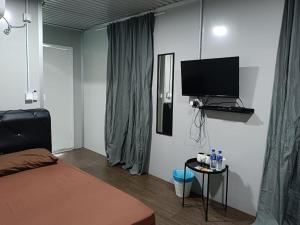 1 dormitorio con 1 cama y TV de pantalla plana en Ghumoh Safar (Bed,Pool & Cafe), en Kuala Kangsar