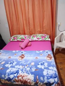 uma pequena cama rosa com flores em Aconchego em Pântano Grande