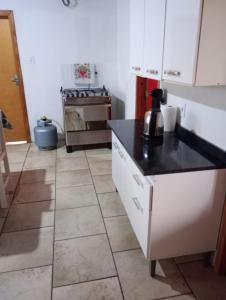 uma cozinha com armários brancos e um balcão preto em Aconchego em Pântano Grande