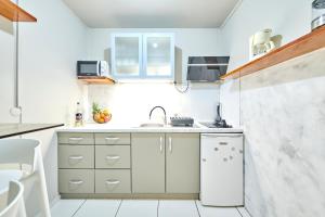 una pequeña cocina con armarios blancos y fregadero en fleur de tranquillité, en Le Gosier
