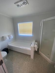 a white bathroom with a toilet and a window at Lakeside Taupo Motel in Taupo